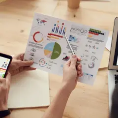 Analiza danych z Yandex Metrica na papierze i ekranie telefonu. Wykresy i diagramy kołowe pokazują kluczowe wskaźniki.
