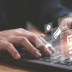 Dłoń na klawiaturze laptopa, ikony koszyka, karty i procentów symbolizują pozycjonowanie Magento i e-commerce.