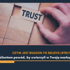 Dłoń układa kostkę z napisem "TRUST". To kluczowy element marketingu, dający klientom reason to believe w Twoją markę.
