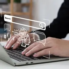 Osoba pracuje nad laptopem, nad którym wyświetla się grafika symbolizująca wyszukiwanie i sztuczną inteligencję, kluczowe elementy skutecznej strategii SEO.