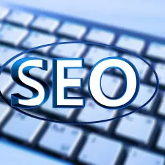 Niebieskie litery "SEO" na tle klawiatury. Unikaj black hat seo, postaw na uczciwe pozycjonowanie.