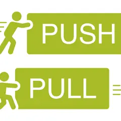 Dwie zielone tabliczki z napisami PUSH i PULL. Obok PUSH postać popycha, obok PULL ciągnie. Ilustracja strategii push i pull.