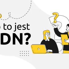 Dwie osoby dyskutują o tym, co to jest skrót CDN. Jedna z nich pokazuje dokument, a druga pracuje przy laptopie.