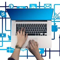 Ręce na klawiaturze laptopa, otoczone ikonami mediów społecznościowych i usług, tworzą sieć połączeń, symbolizującą pętlę przekierowań w cyfrowym świecie.
