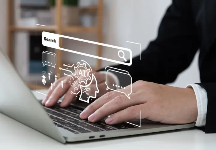 Osoba pracuje nad laptopem, nad którym wyświetla się grafika symbolizująca wyszukiwanie i sztuczną inteligencję, kluczowe elementy skutecznej strategii SEO.