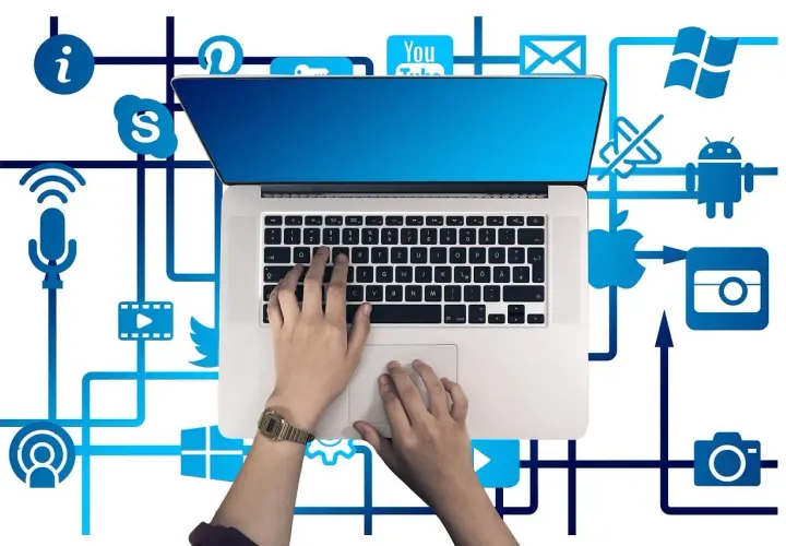 Ręce na klawiaturze laptopa, otoczone ikonami mediów społecznościowych i usług, tworzą sieć połączeń, symbolizującą pętlę przekierowań w cyfrowym świecie.