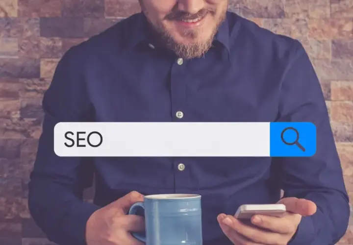 Mężczyzna z kubkiem kawy i telefonem szuka w internecie informacji o SEO. W pasku wyszukiwania widnieje hasło "SEO", sugerujące poszukiwanie w katalogu stron.