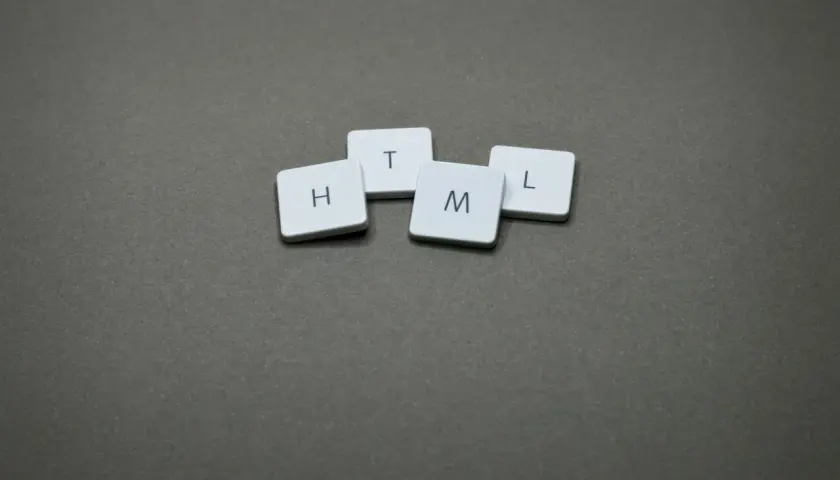 Litery H, T, M, L ułożone na szarym tle. Idealne do c# poradnik o podstawach web developmentu.