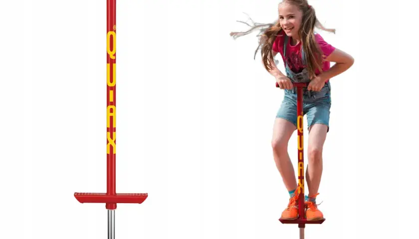Dziewczynka z radością skacze na czerwonym pogo sticku.