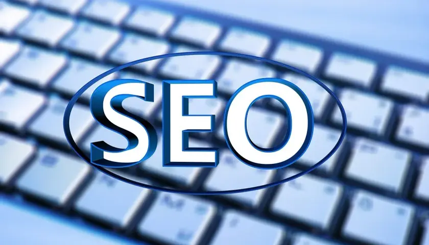 Niebieskie litery "SEO" na tle klawiatury. Unikaj black hat seo, postaw na uczciwe pozycjonowanie.