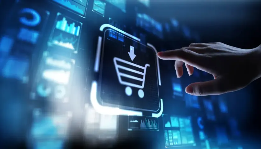 Dłoń dotyka ikony koszyka na ekranie, symbolizując zakupy online i rozwój e-commerce.