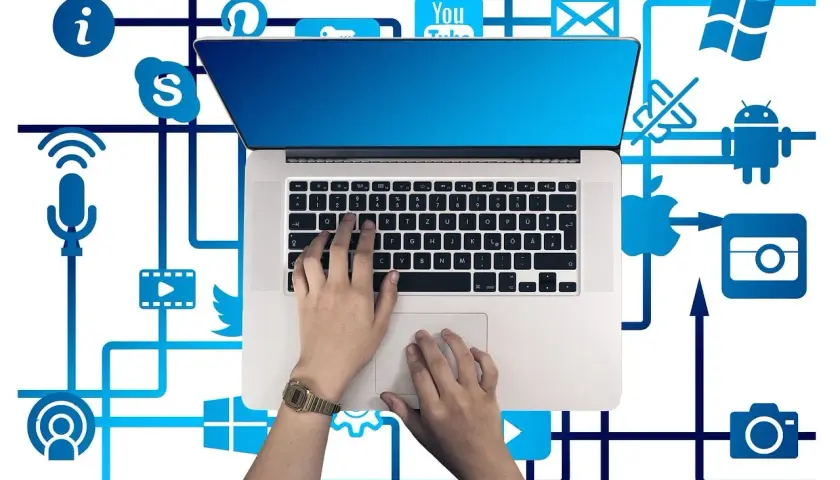 Ręce na klawiaturze laptopa, otoczone ikonami mediów społecznościowych i usług, tworzą sieć połączeń, symbolizującą pętlę przekierowań w cyfrowym świecie.