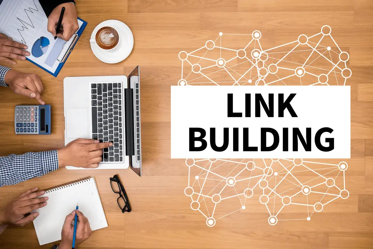 Zespół pracuje nad strategią link buildingu. Na stole laptop, kalkulator, notatnik i kawa.