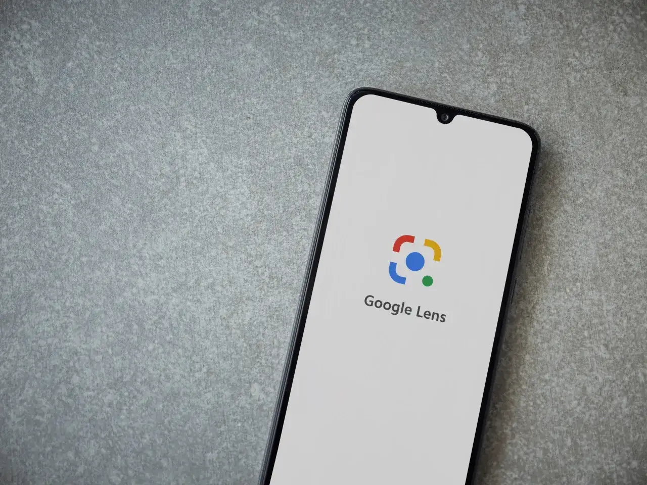 Telefon z logo Google Lens. Możesz go użyć, by szukać zdjęciem i odkrywać świat.